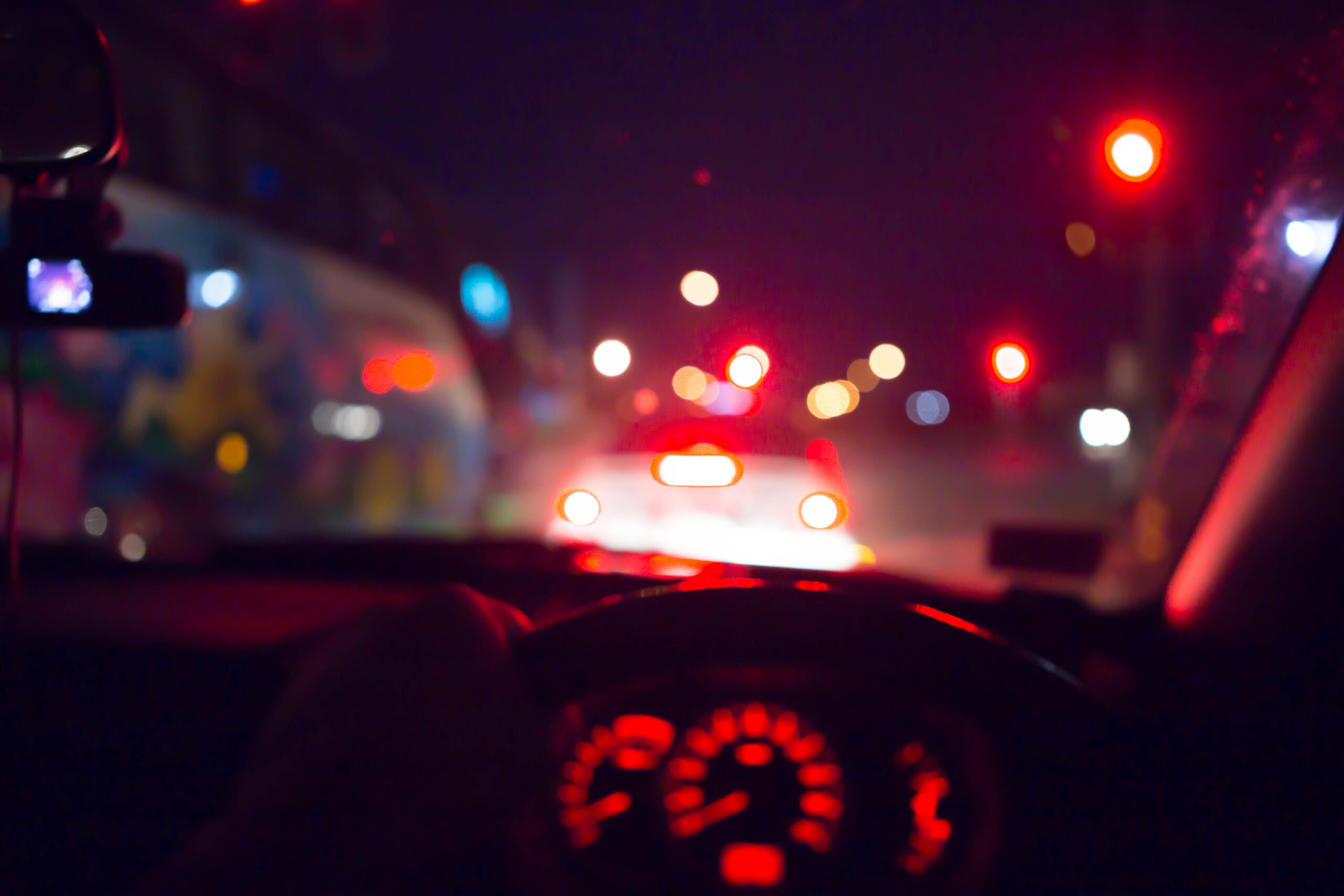 Inside car with bokeh lights from traffic on night time for background.
